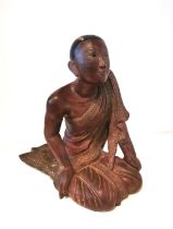 A 19th/early 20th century carved and lacquered Burmese kneeling figure of a monk wearing a robe. The