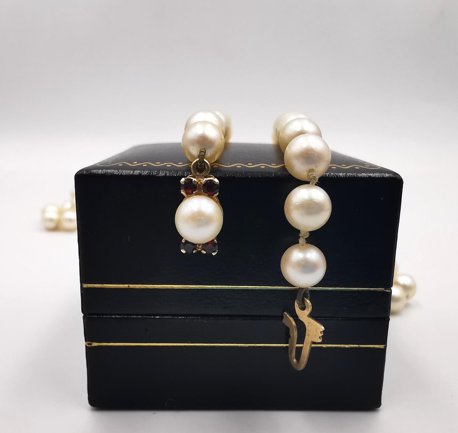 A long knotted string of graduated cultured pearls with 9ct yellow gold red stone set hook and - Image 8 of 8