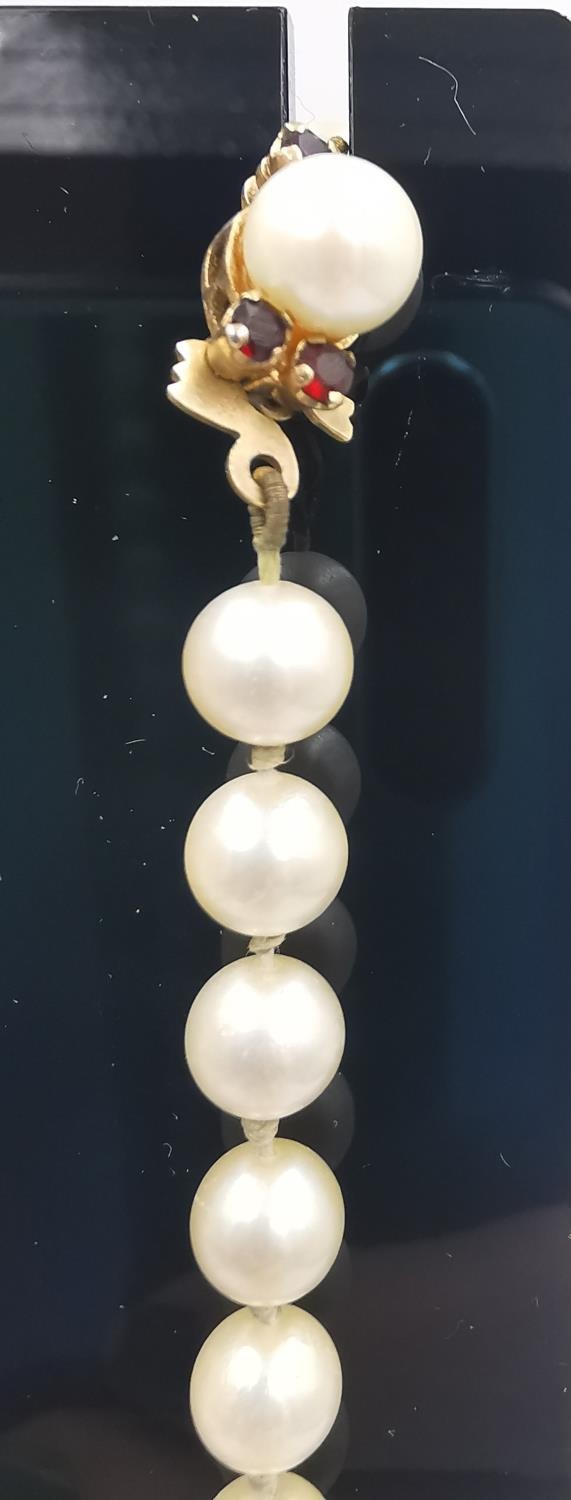 A long knotted string of graduated cultured pearls with 9ct yellow gold red stone set hook and - Image 2 of 8