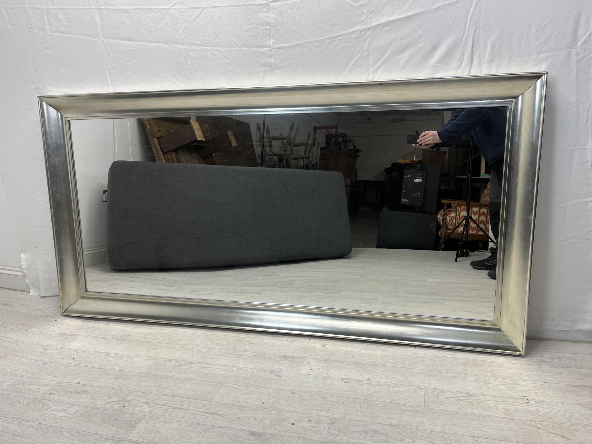 A large contemporary wall mirror in silvered frame. H.100 W.200cm.