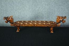 A hardwood decorative Mancala board game in the shape of a dragon. With carved decoration and