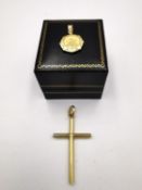 A yellow metal (tests as 18ct yellow gold) simple cross and 18ct yellow gold repousse medallion with