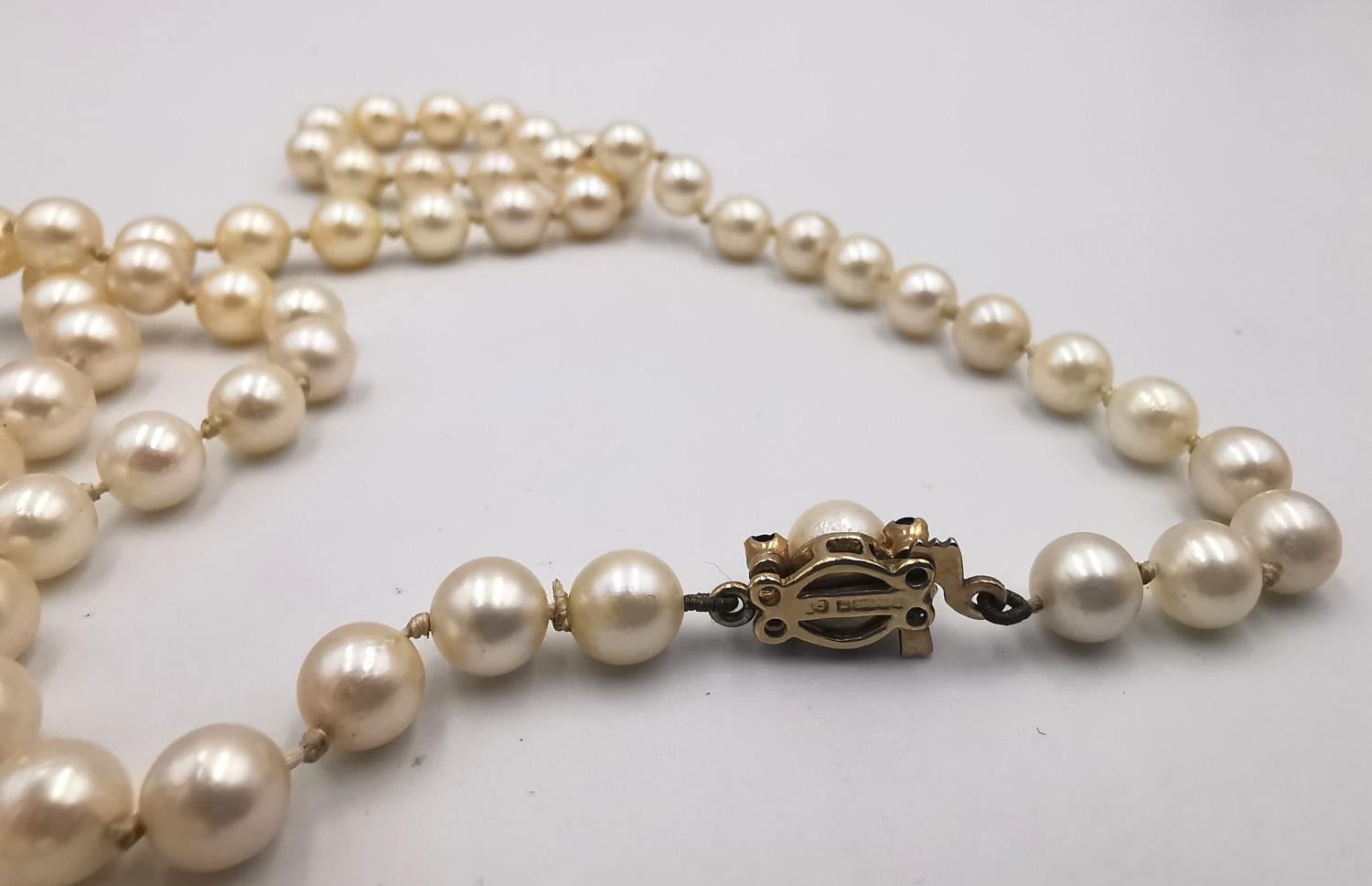 A long knotted string of graduated cultured pearls with 9ct yellow gold red stone set hook and - Image 6 of 8