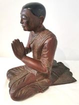 A 19th/early 20th century carved and lacquered Burmese kneeling figure of a praying monk wearing a