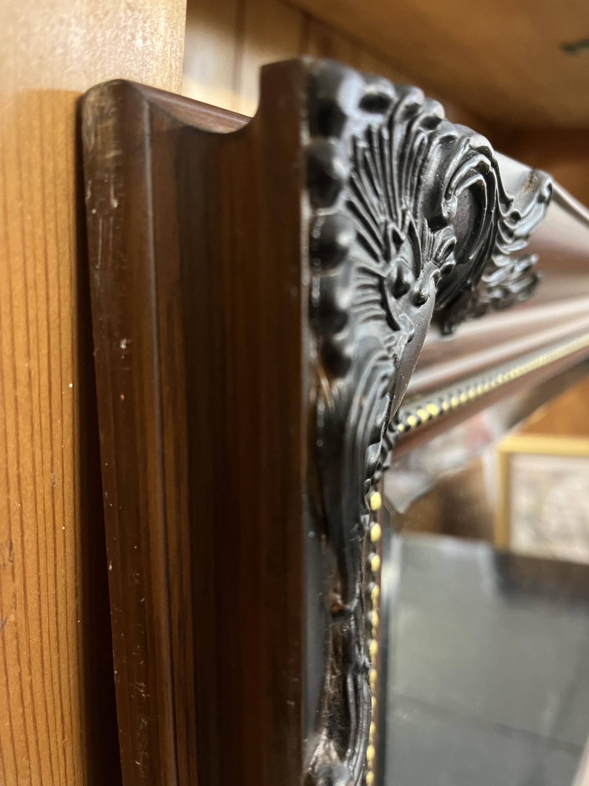 A contemporary wall mirror with foliate frame and bevelled plate. H.76 W.106cm. - Image 3 of 4