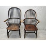 Two 19th century elm seated hoop back Windsor armchairs on turned and stretchered supports.