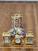 A Crown Derby sleeping cat and four Halcyon Days miniature clocks. Cat is 8cm long.