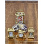 A Crown Derby sleeping cat and four Halcyon Days miniature clocks. Cat is 8cm long.