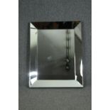 A contemporary wall mirror set in a glazed frame. H.96 W.76cm.