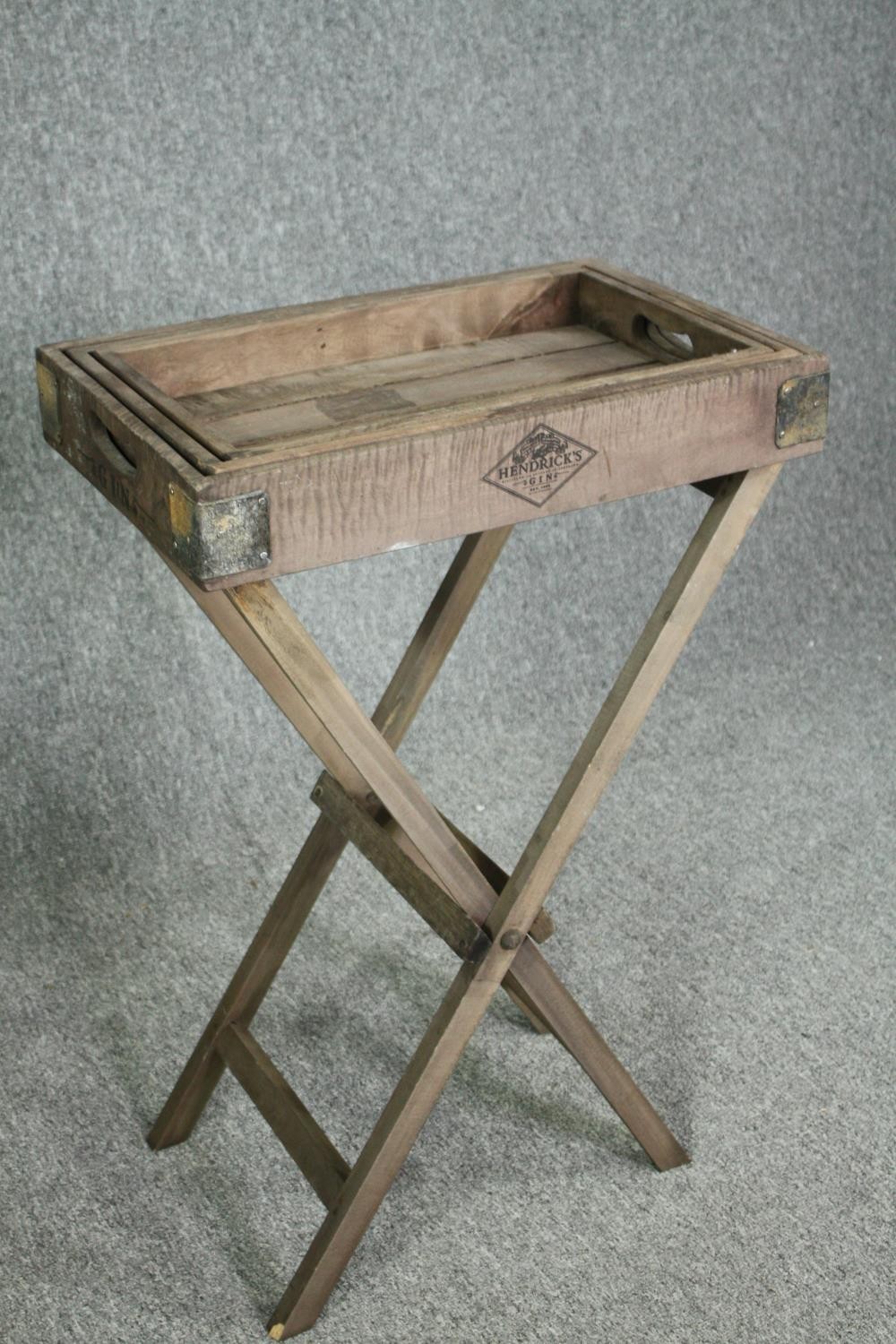 A set of three graduating fitted trays on a folding stand. H.80 W.52 D.33cm.