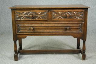 A mid century Ipswich oak side cabinet in the Jacobean style with carved flowerhead and linen fold