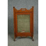 A late 19th century Arts and Crafts oak fire screen inset with a glazed needlework sampler. H.81 W.