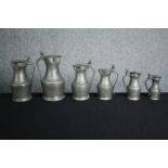A set of six 19th century graduating pewter lidded jugs. H.27cm. (largest)