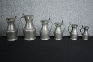 A set of six 19th century graduating pewter lidded jugs. H.27cm. (largest)