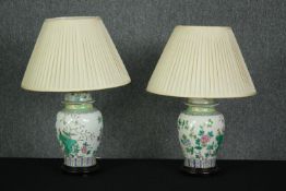 A pair of Chinese Famille Verte style baluster form table lamps with their shades on hardwood bases.