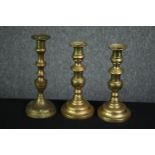 A pair of 19th century brass candlesticks and another similar. H.24cm (largest).