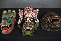 A collection of four carved and painted Eastern polychrome masks. H.38cm. (largest).