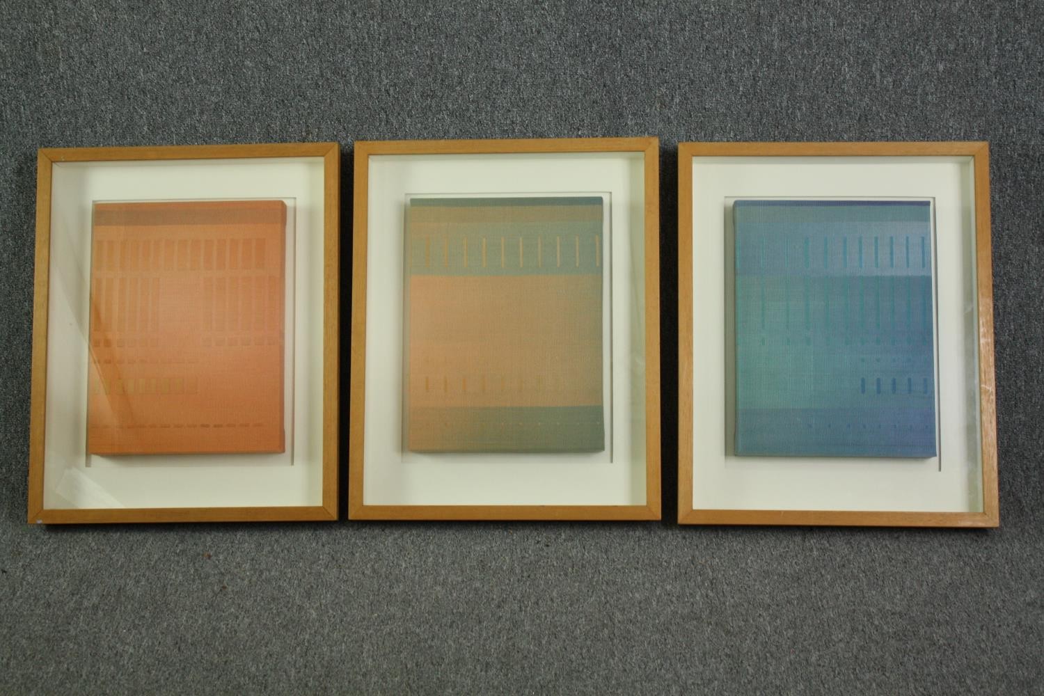 A set of three contemporary framed and glazed abstract fabric artworks. H.61 W.49cm. (each).