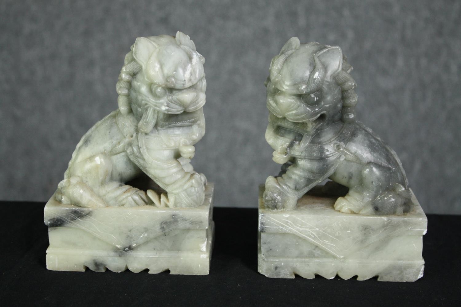A pair of Chinese carved soapstone foo dogs. H.14cm. (each).