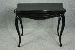 A 19th century ebonised foldover top games table on slender Louis XV style cabriole supports. H.69