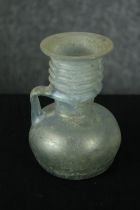 A Roman iridescent glass oil jug. H.12cm.