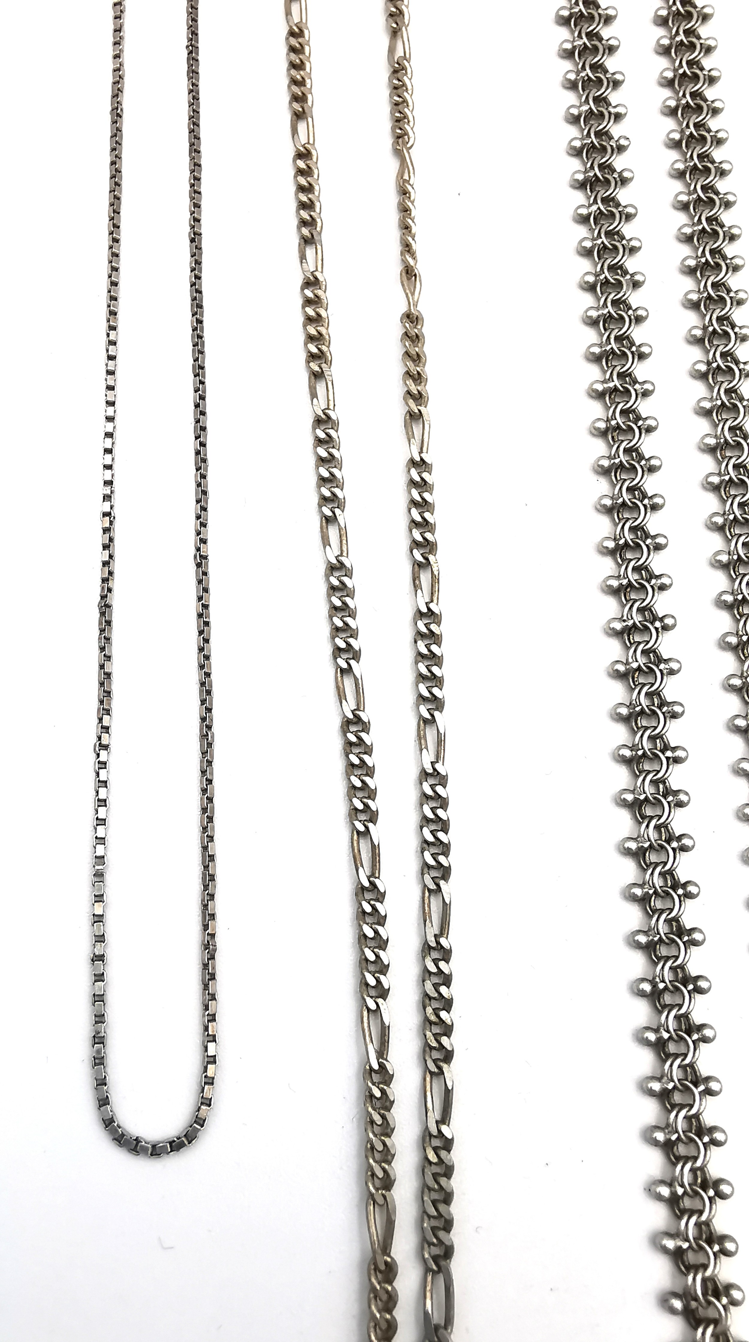 A collection of silver chains of varying length and a white metal rollerball link bracelet. - Image 4 of 4