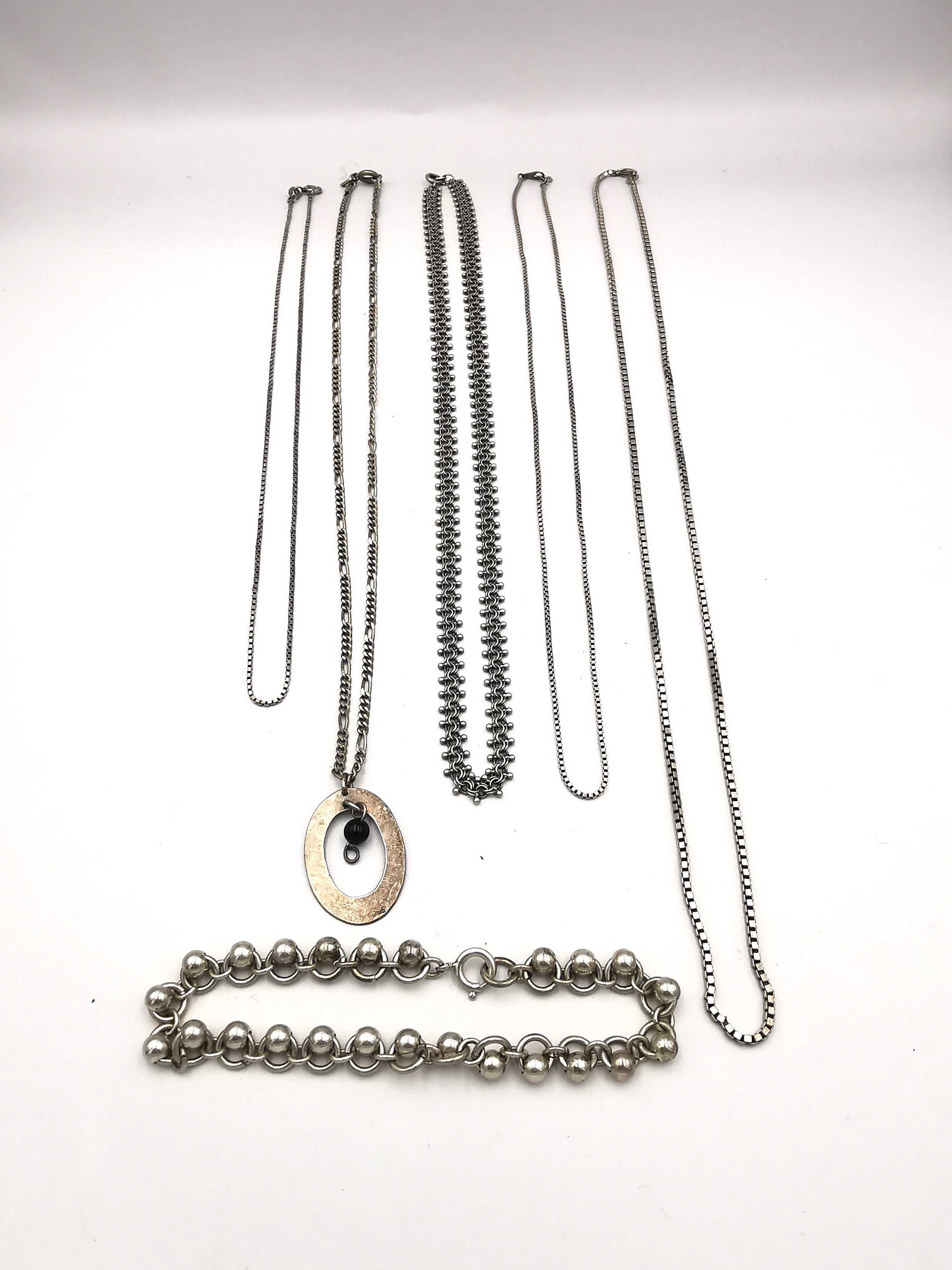 A collection of silver chains of varying length and a white metal rollerball link bracelet.