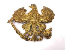 A WWI Prussian helmet badge impressed brass emblem with eagle design, holding a ball and sceptre,