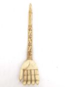 A 19th century Indian carved bone back scratcher in the form of a hand, with inset pink stones.