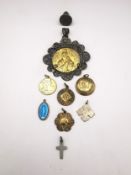 A collection of religious medallions, including a filigree wirework medallion of Mary and Jesus, a
