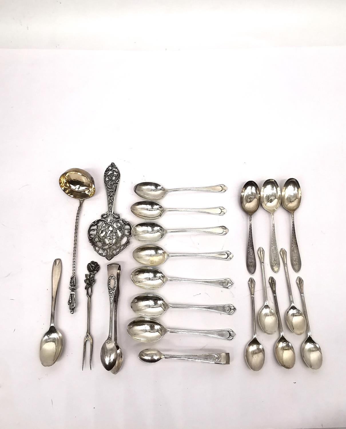 A collection of silver teaspoons, two pairs of sugar tongs, a pickle fork, a small sauce ladle and a