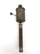 A Tibetan 19th century brass and copper repousse prayer wheel with hardwood handle. H.31cm.