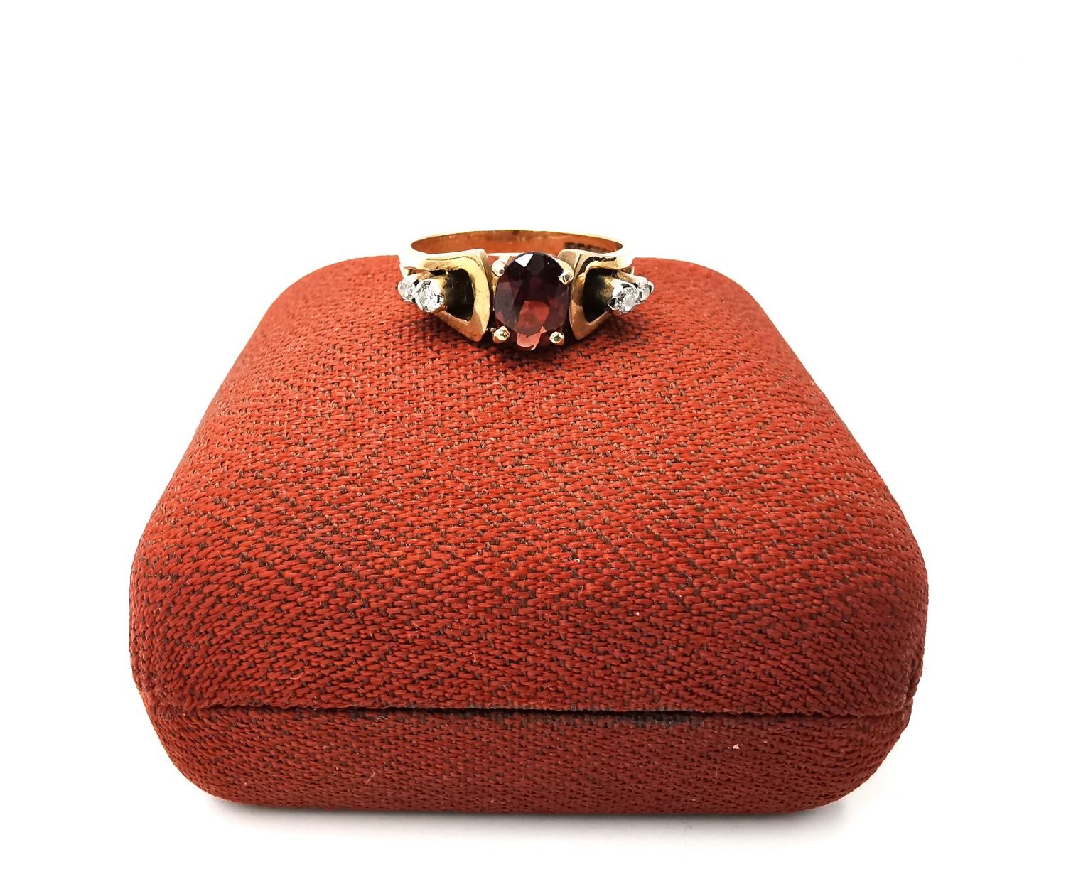 A boxed 1970's 9ct yellow gold sculptural design garnet and diamond dress ring, set to centre with