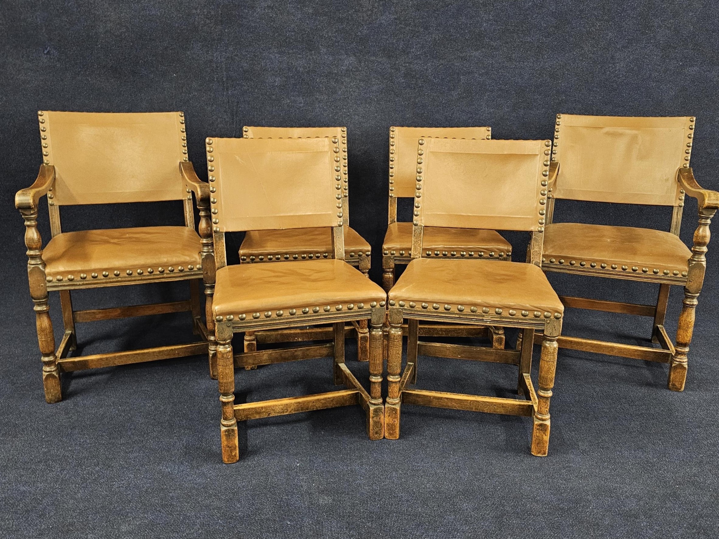 A set of six mid century oak framed dining chairs in the Jacobean style. Upholstered in leather to