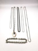A collection of silver chains of varying length and a white metal rollerball link bracelet.