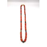 A vintage coral necklace with cylindrical metal pierced beads and gold plated spacers. Fastens