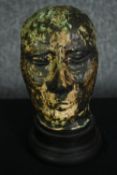 A ceramic glazed bust; man's head on ebonised socle. H.23cm.