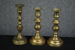 A pair of 19th century brass candlesticks and another similar. H.24cm (largest).