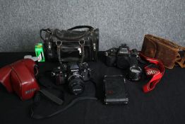 Two vintage cameras; Nikon and Canon along with various accessories. H.15 W.25cm. (largest).