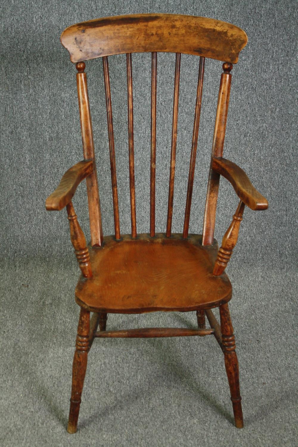 A 19th century elm seated stick back kitchen chair.