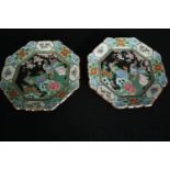 A pair of early 20th century Famille noire hand painted octagonal plates with peacock and floral