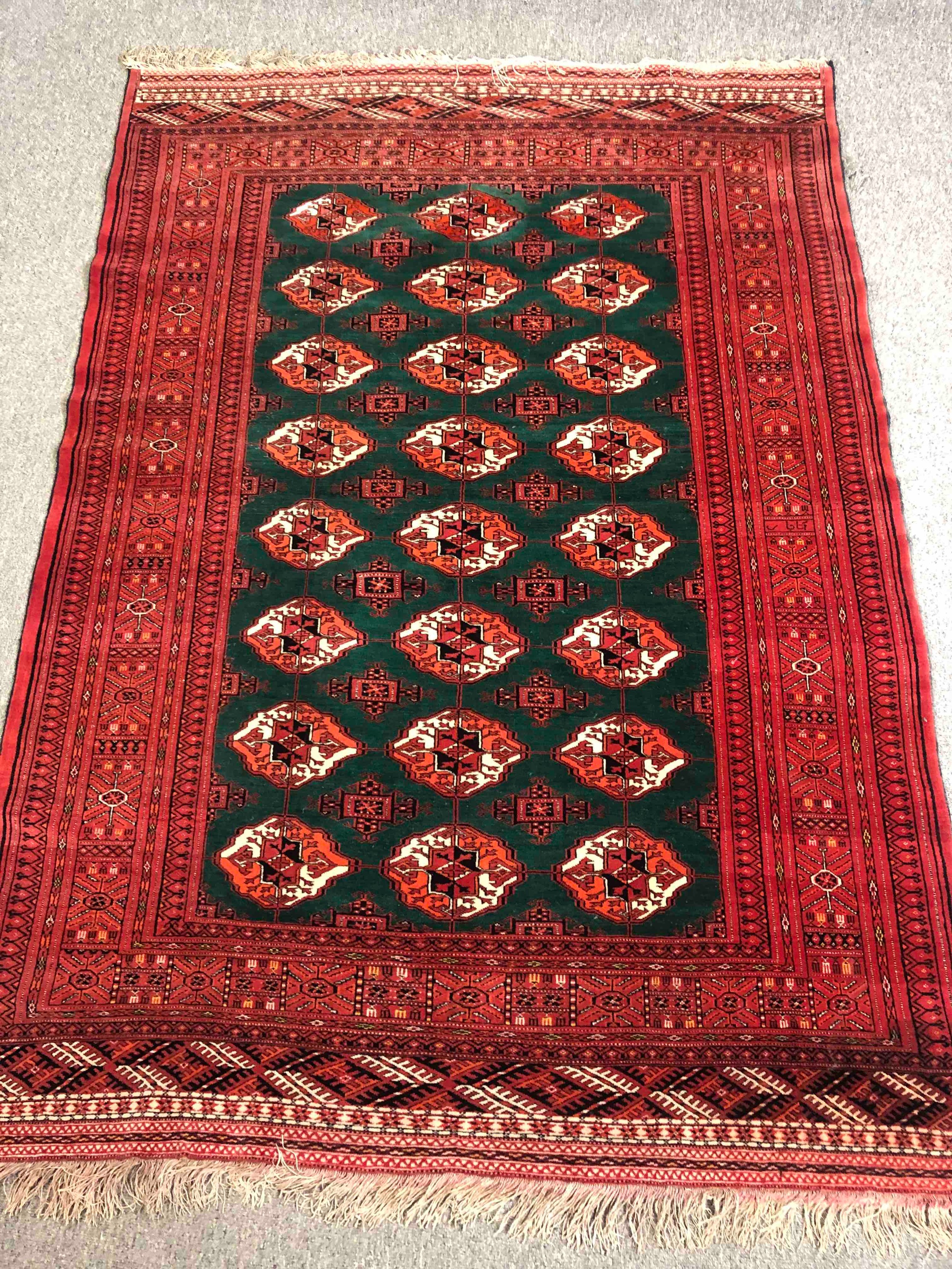 A Bokhara carpet with repeating gul motifs across the field within broad multiple stylised