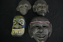 A collection of four carved hardwood masks. H.28 W.25cm. (largest).