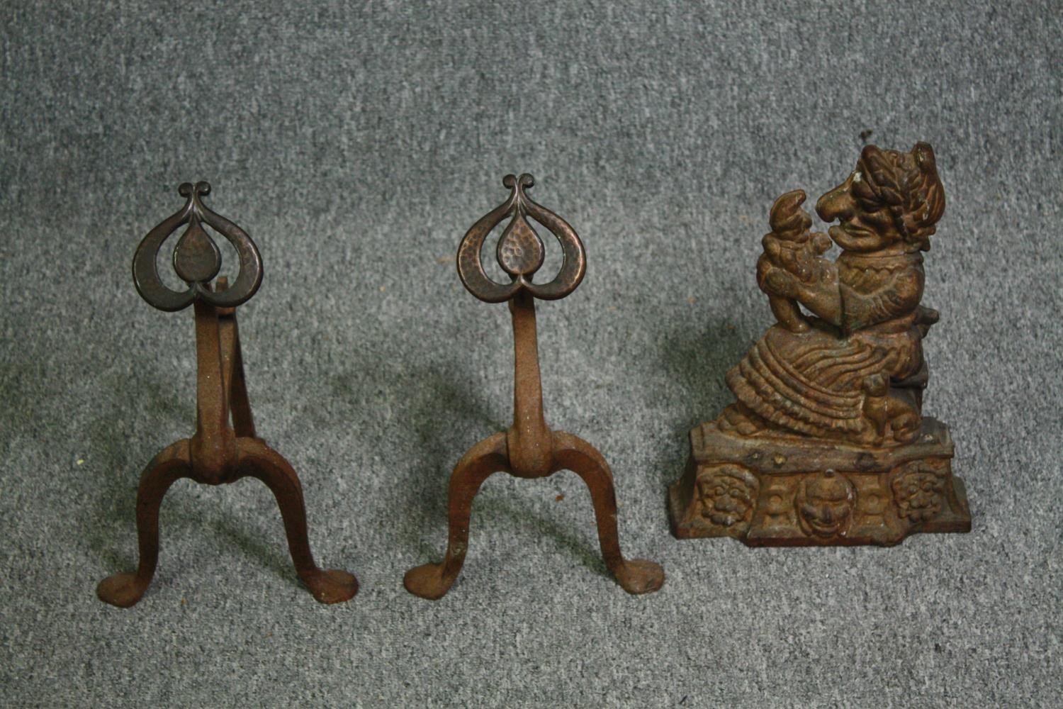 A pair of late 19th century Art Nouveau iron fire dogs and an iron doorstop. H.34cm. (largest).