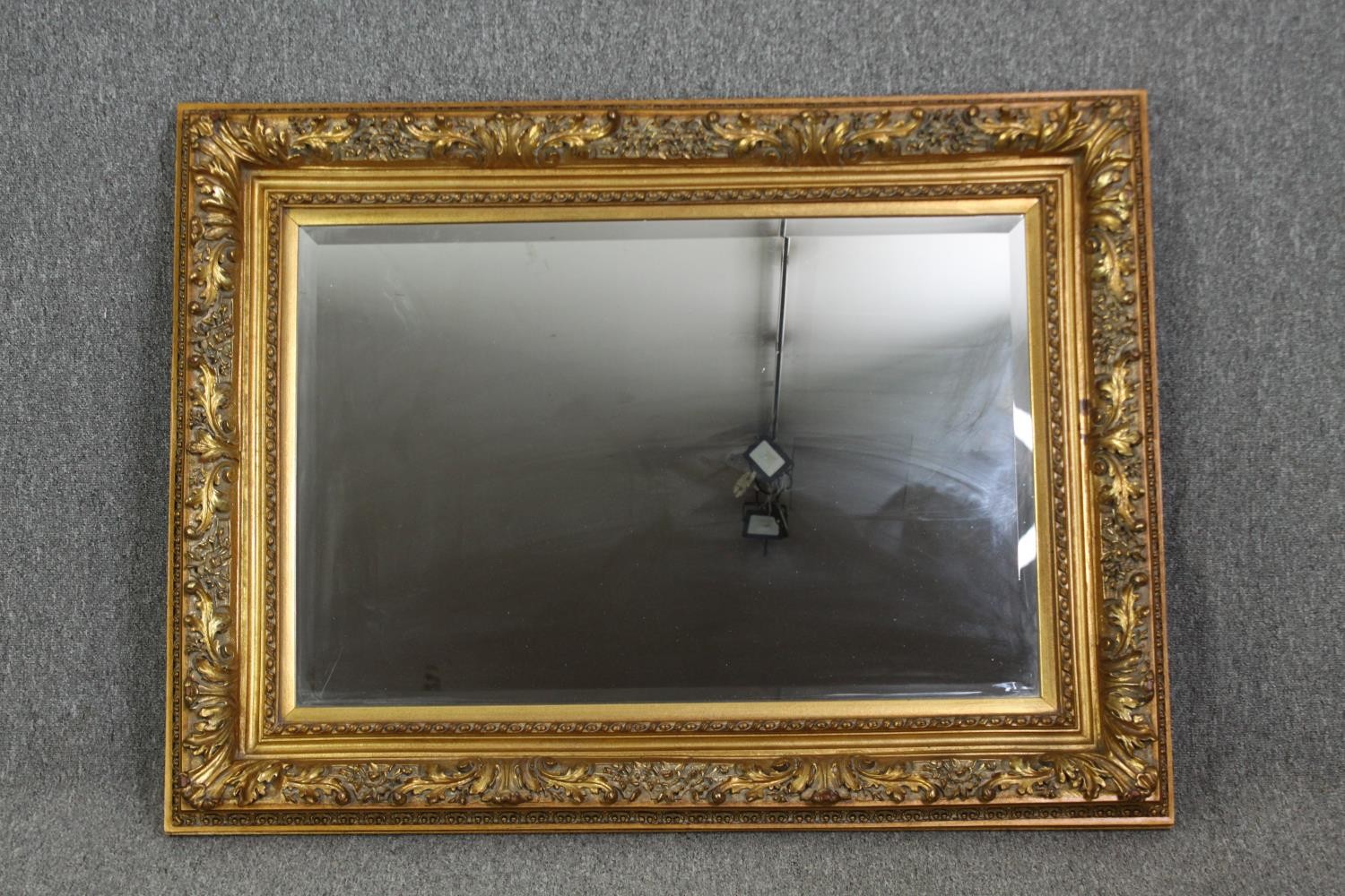 A giltwood and gesso wall mirror with foliate decoration and bevelled plate. H.91 W.120cm.