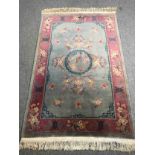 A Chinese woollen carpet with central flowerhead medallion within complementary burgundy borders.
