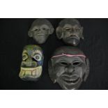 A collection of four carved hardwood masks. H.28 W.25cm. (largest).