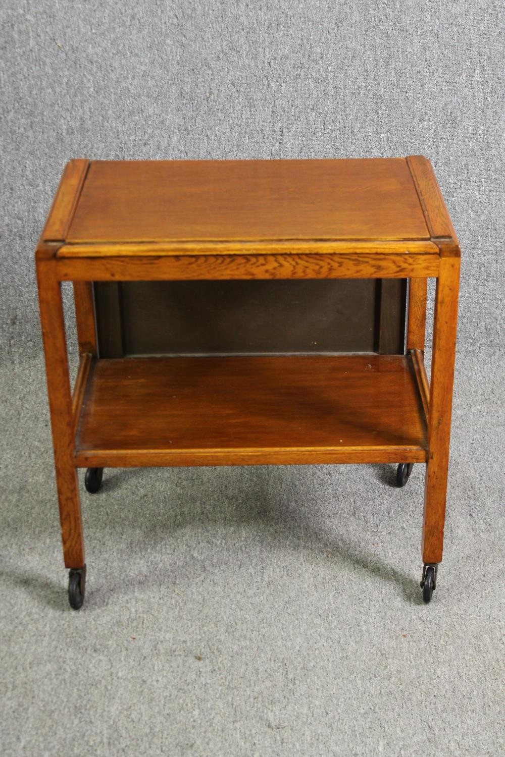 A mid century light oak serving or drinks trolley with spring action drop side. H.66 W.80 D.64cm.