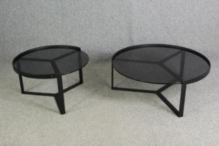 Two contemporary coffee tables with tinted glass tops and black metal supports. H.35 Dia.89cm. (