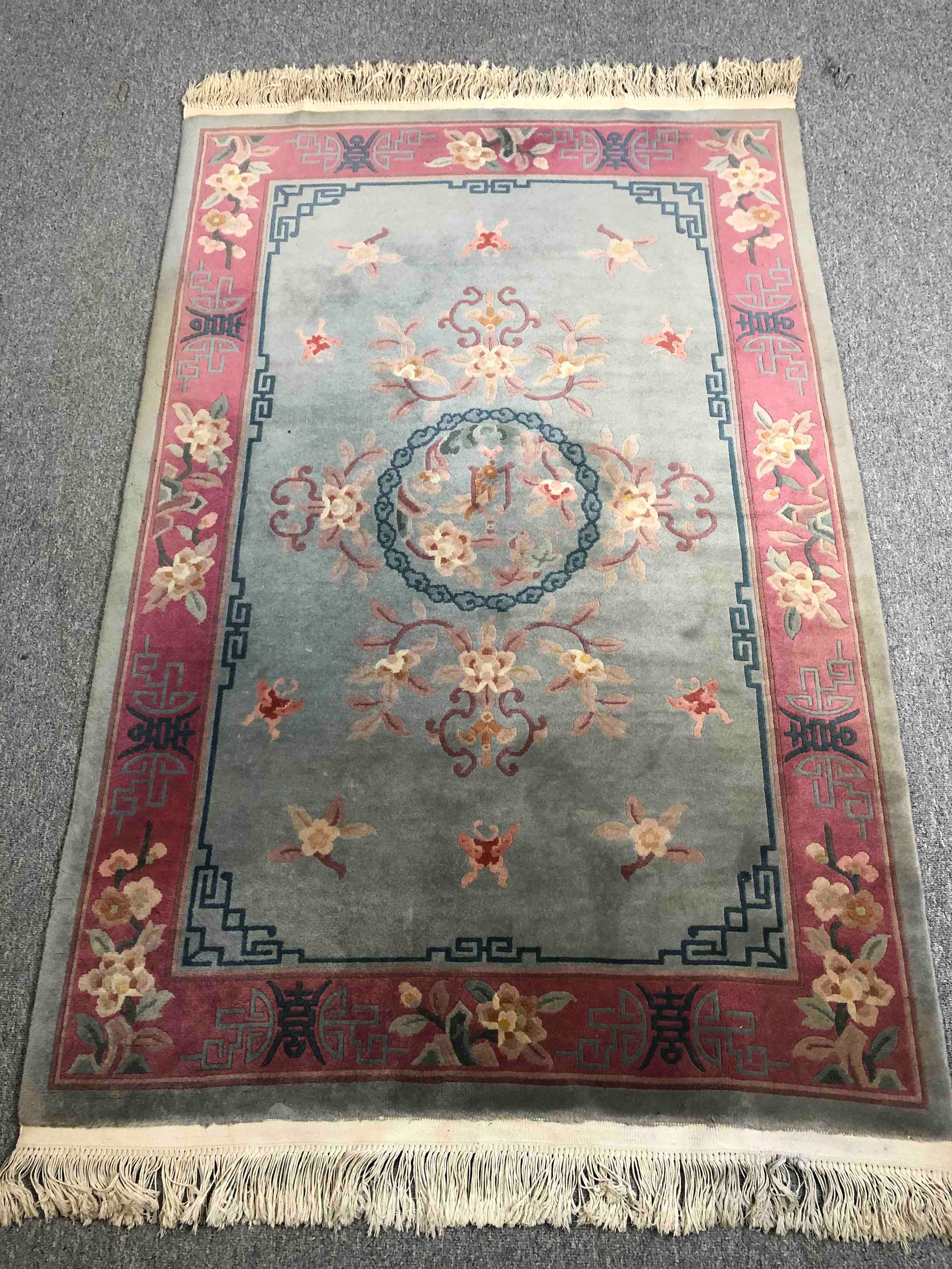 A Chinese woollen carpet with central flowerhead medallion within complementary burgundy borders.